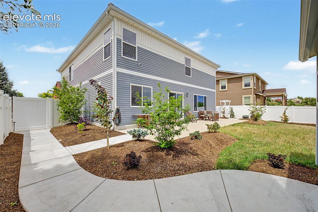 Image 36 of 43: A wide concrete walkway guides you through the lushly landscaped side yard