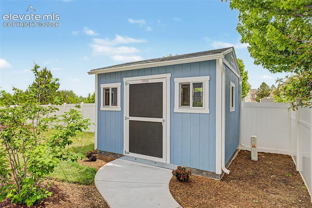 Image 37 of 43: A substantial storage shed with windows and a ramp sits neatly in the corne