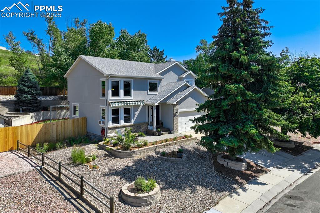 Caption: Traditional-style home featuring stucco siding, roof with shingles, stone siding, and a garage
