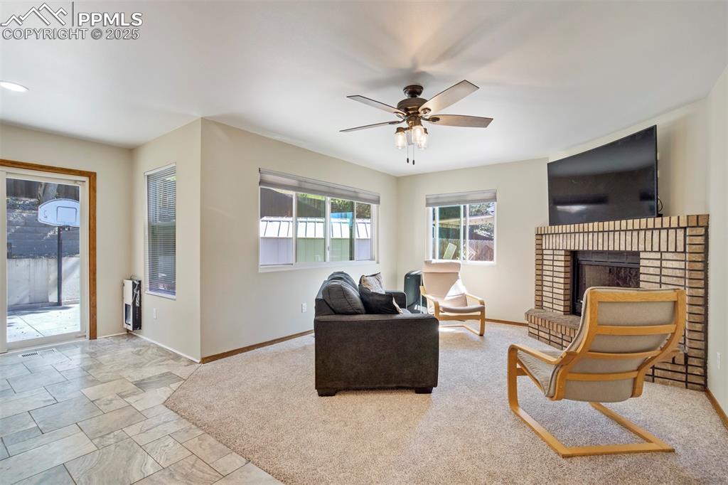 Image 12 of 50: Living area with a ceiling fan, a fireplace, and heating unit