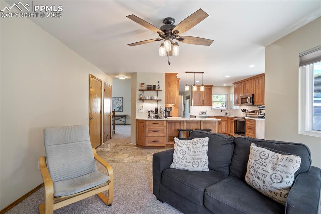Image 14 of 50: Living area featuring ceiling fan, light stone finish floors, recessed ligh