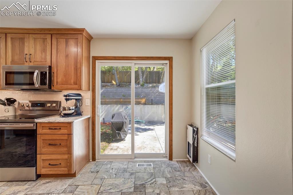 Image 16 of 50: Kitchen featuring appliances with stainless steel finishes, light stone fin