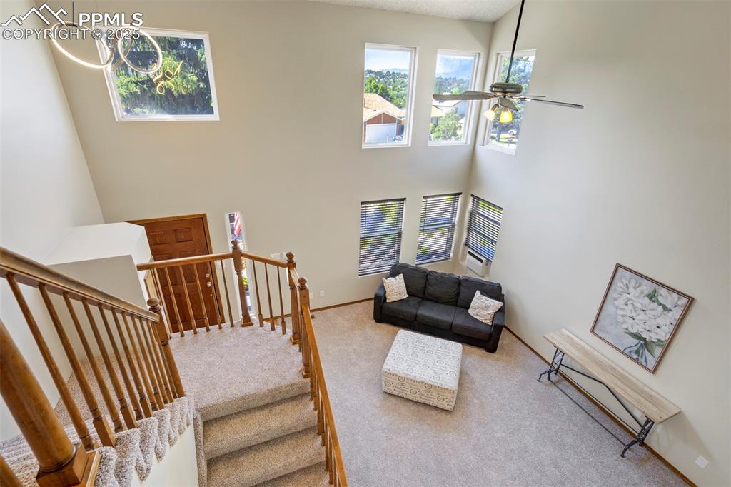 Image 20 of 50: Stairway with carpet floors, ceiling fan, and a towering ceiling