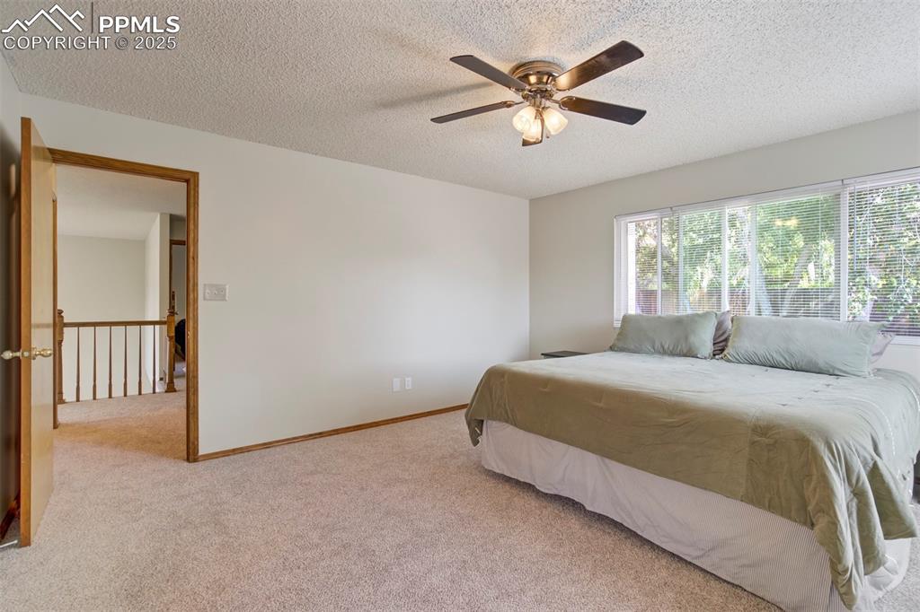 Image 22 of 50: Bedroom with light colored carpet, a textured ceiling, and a ceiling fan