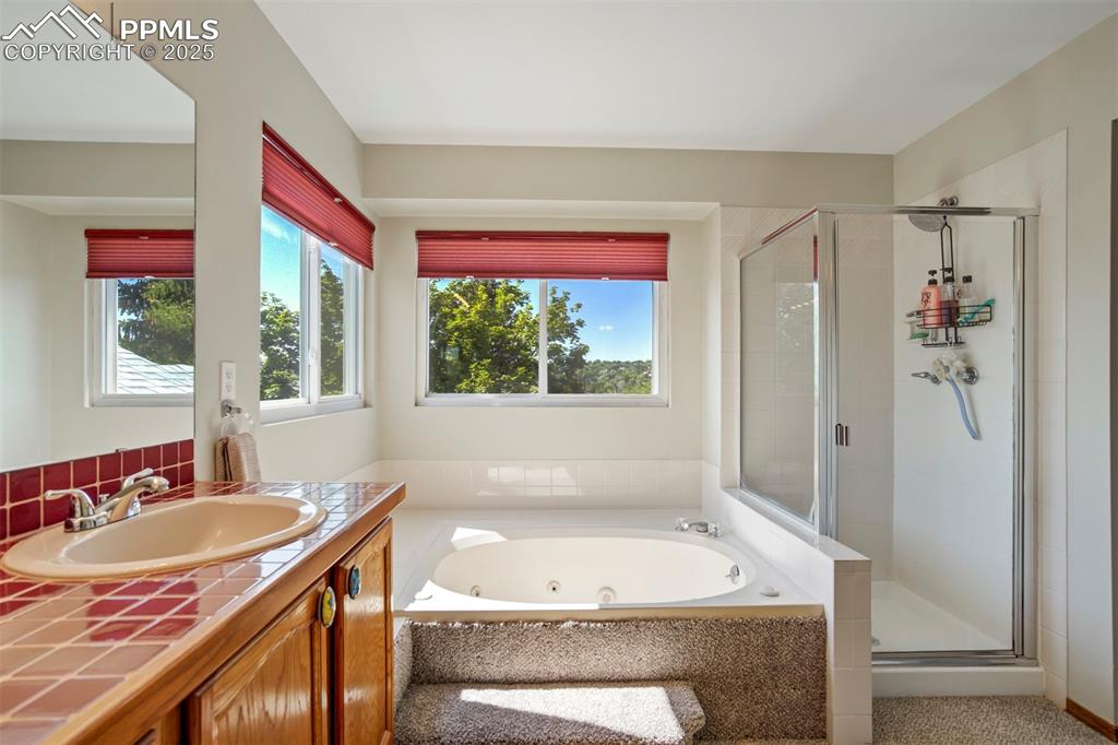 Image 24 of 50: Bathroom featuring a shower stall, a jetted tub, and vanity