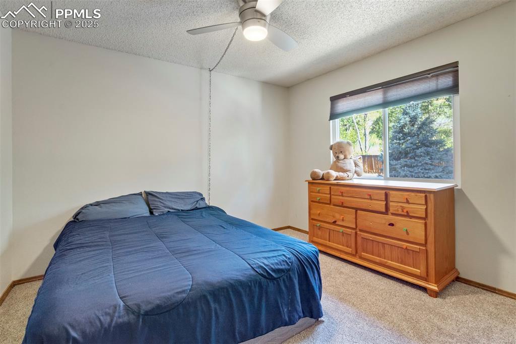 Image 28 of 50: Bedroom featuring light carpet, a textured ceiling, and ceiling fan