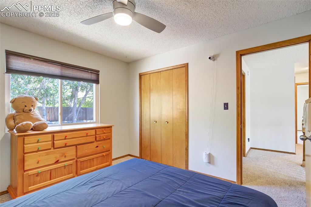 Image 29 of 50: Bedroom with a textured ceiling, carpet flooring, a closet, and ceiling fan
