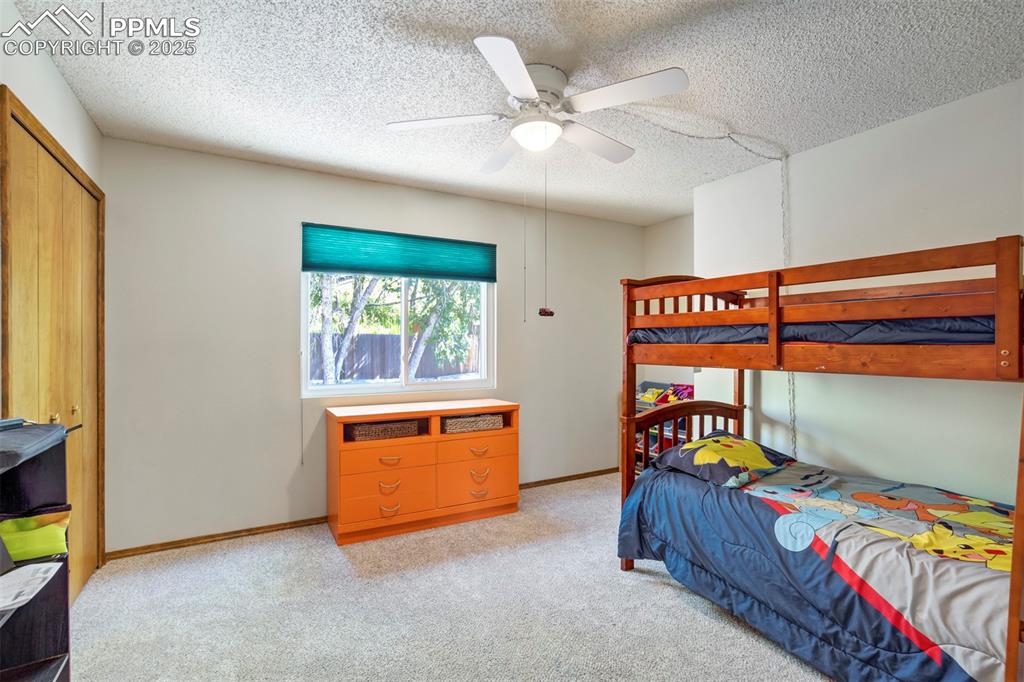 Image 30 of 50: Bedroom featuring light carpet, a textured ceiling, a ceiling fan, and a cl