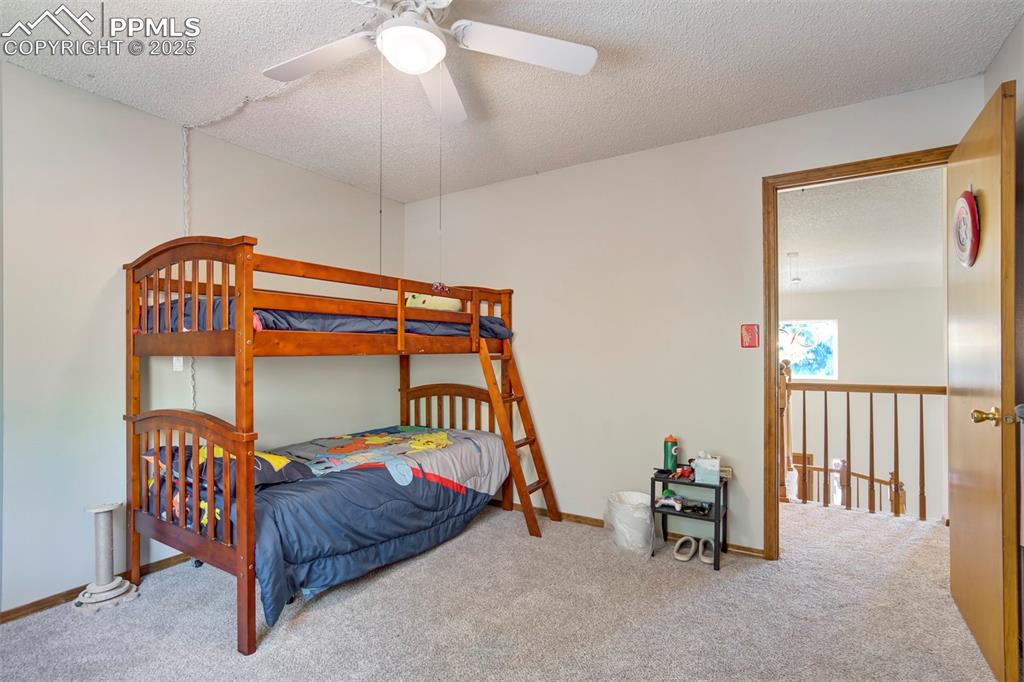 Image 31 of 50: Carpeted bedroom featuring a textured ceiling and a ceiling fan