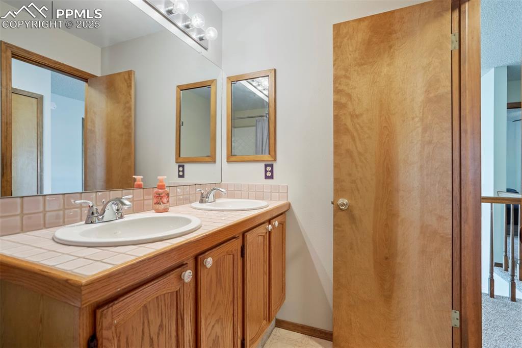 Image 34 of 50: Bathroom with double vanity and tasteful backsplash