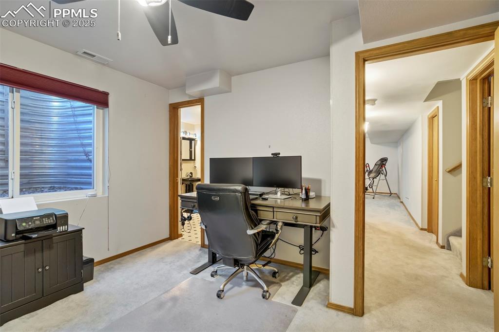 Image 40 of 50: Office with light colored carpet and a ceiling fan