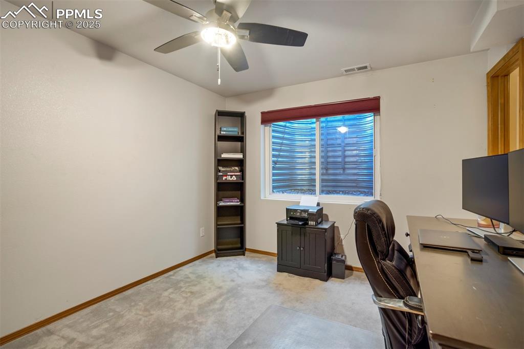 Image 41 of 50: Office area with light colored carpet and a ceiling fan