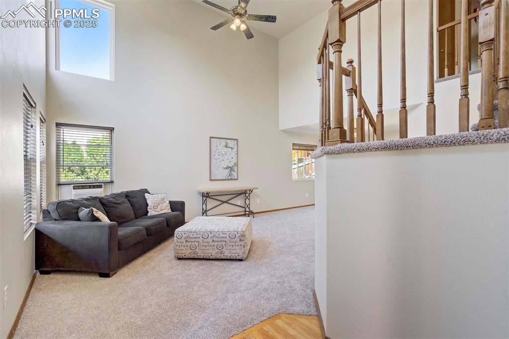 Image 5 of 50: Carpeted living area featuring a towering ceiling, plenty of natural light,