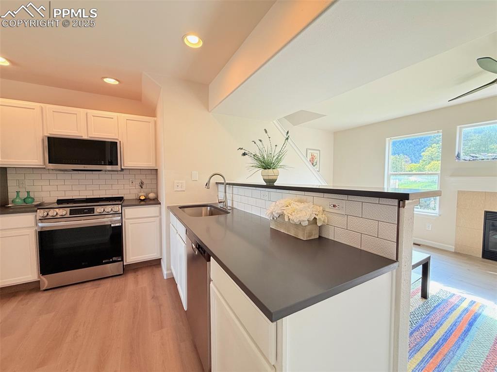 Image 11 of 44: Kitchen with stainless steel appliances, a peninsula, white cabinetry, a ti