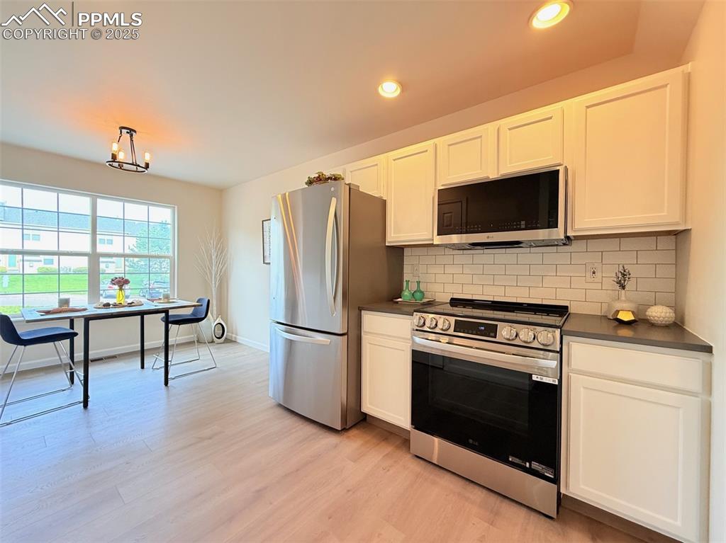 Image 12 of 44: Kitchen featuring dark countertops, appliances with stainless steel finishe