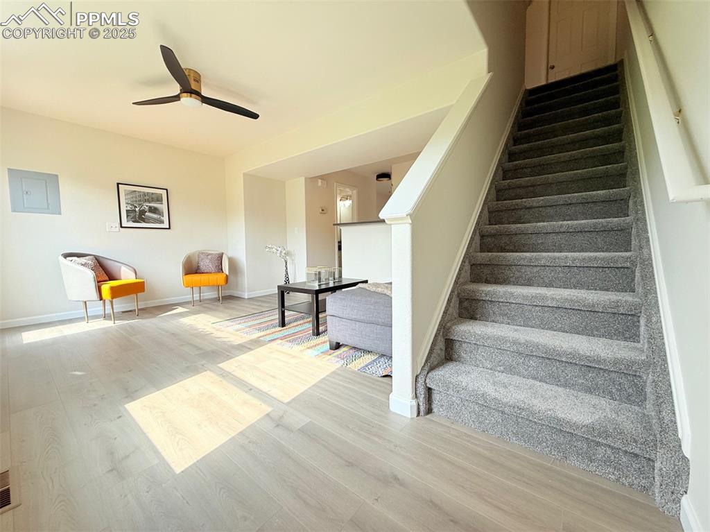 Image 22 of 44: Stairs with wood finished floors, a ceiling fan, and electric panel