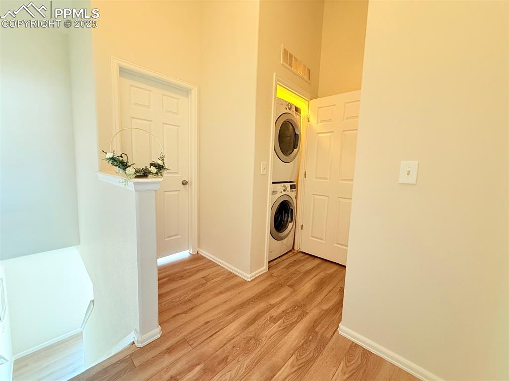 Image 30 of 44: Washroom featuring stacked washer / drying machine, light wood-type floorin