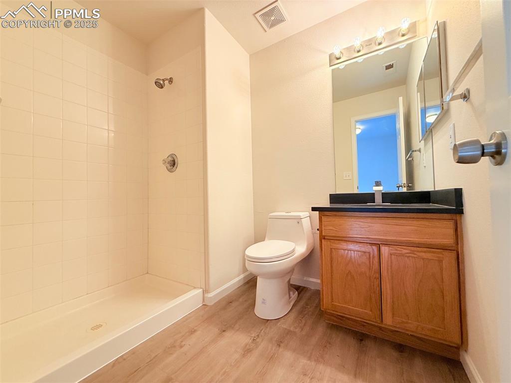 Image 36 of 44: Full bathroom with vanity, light wood-style floors, and tiled shower