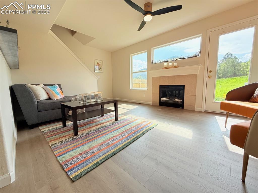 Image 6 of 44: Living room with light wood-type flooring, ceiling fan, a fireplace, and st