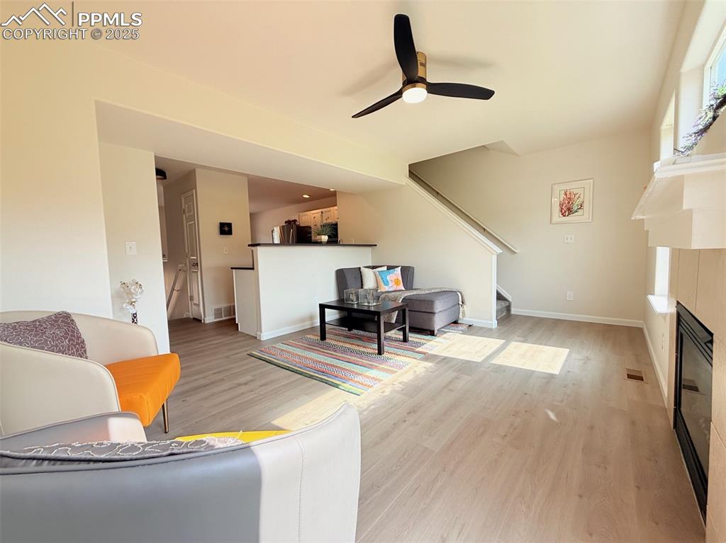 Image 7 of 44: Living room featuring a fireplace, a ceiling fan, light wood-type flooring,