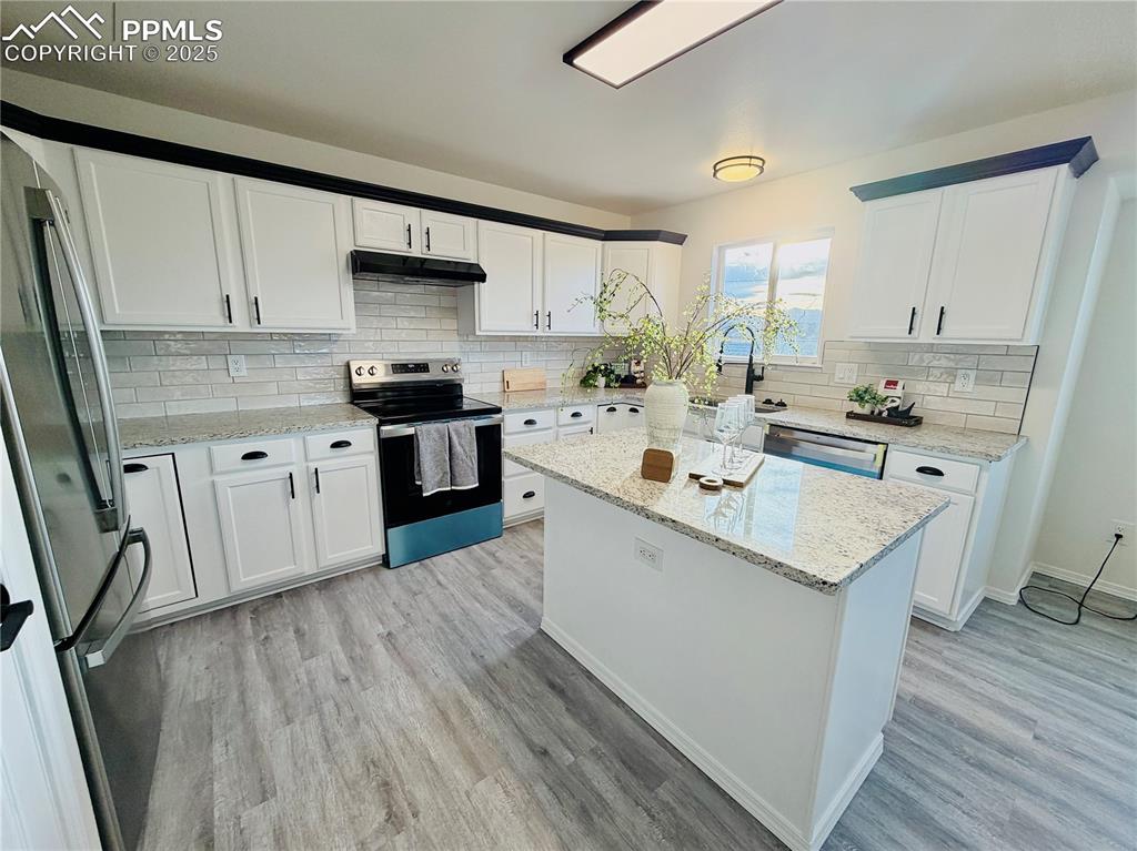 Image 12 of 38: Kitchen featuring appliances with stainless steel finishes, white cabinets,