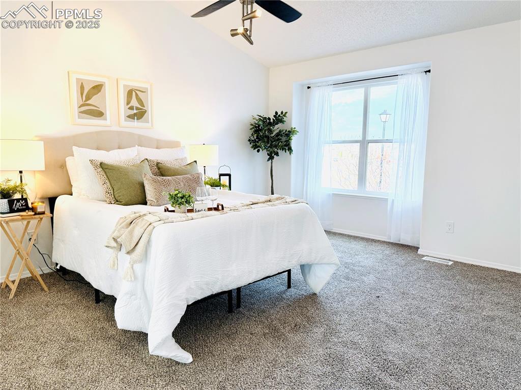 Image 16 of 38: Carpeted bedroom with vaulted ceiling, ceiling fan, and a textured ceiling