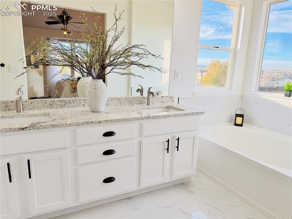 Image 19 of 38: Full bath featuring double vanity, a garden tub, light marble finish floors