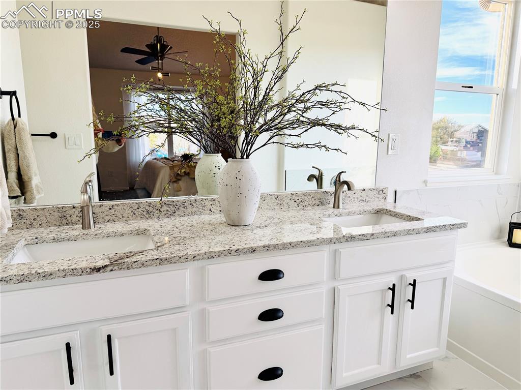 Image 20 of 38: Ensuite bathroom with double vanity, plenty of natural light, and a bath