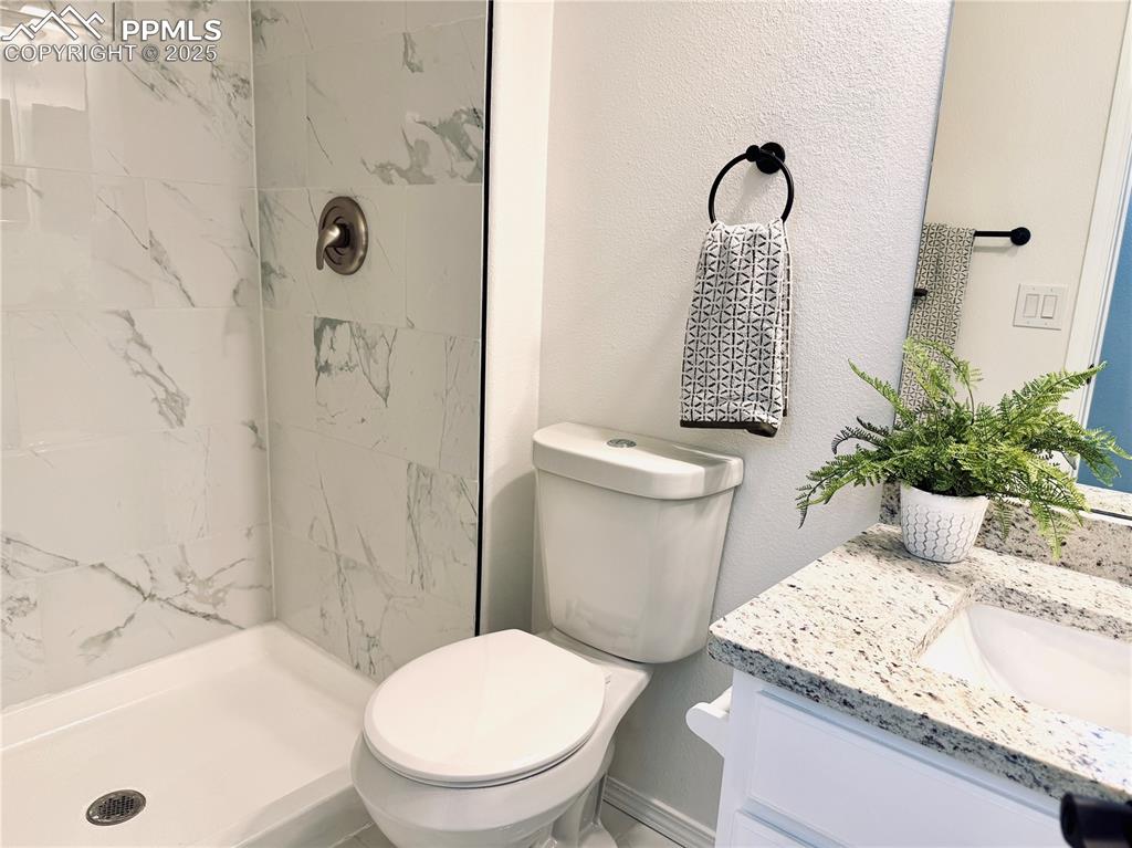 Image 24 of 38: Bathroom with a textured wall, a marble finish shower, and vanity