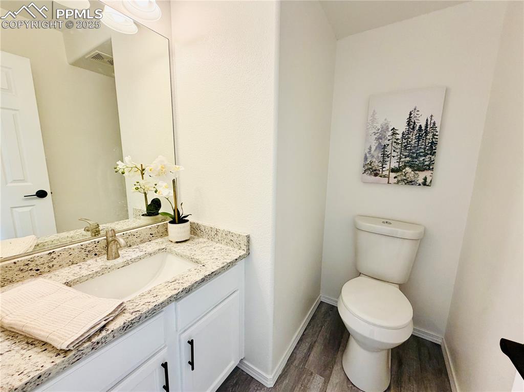 Image 25 of 38: Half bathroom with vanity and dark wood-style floors