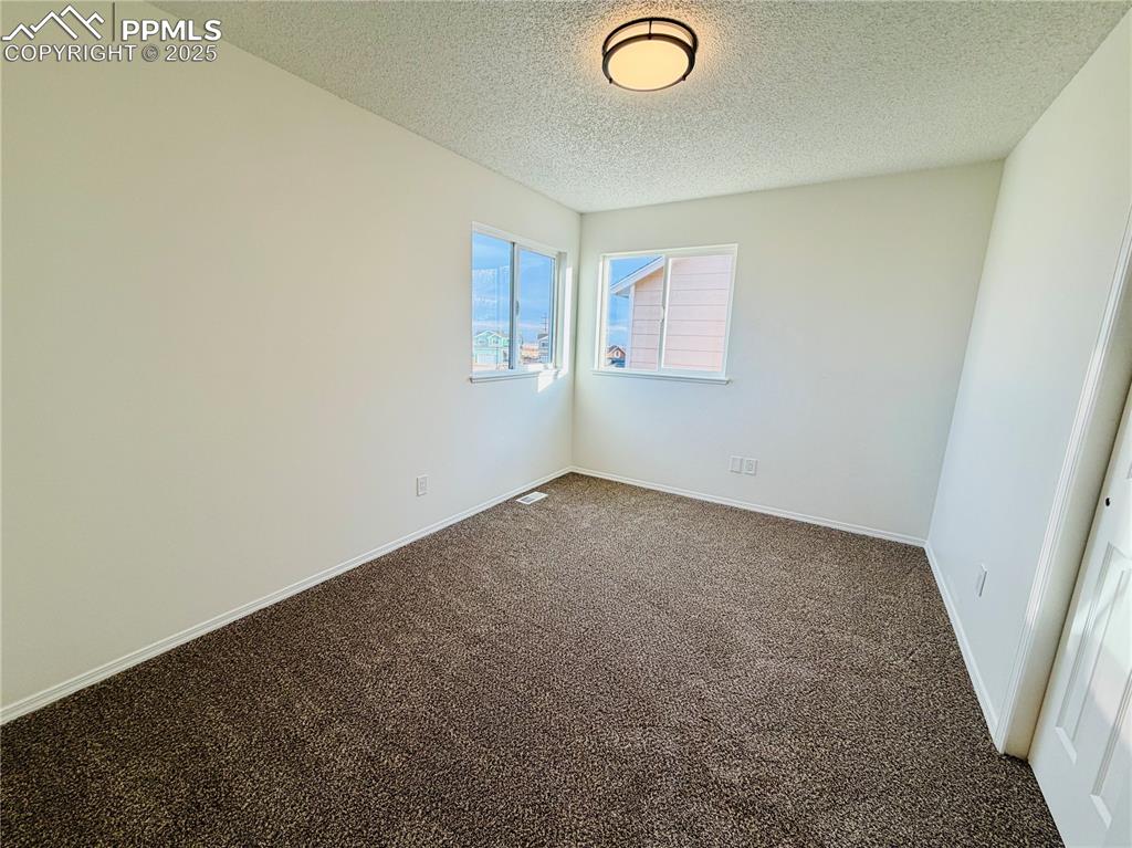 Image 31 of 38: Carpeted empty room with a textured ceiling and baseboards
