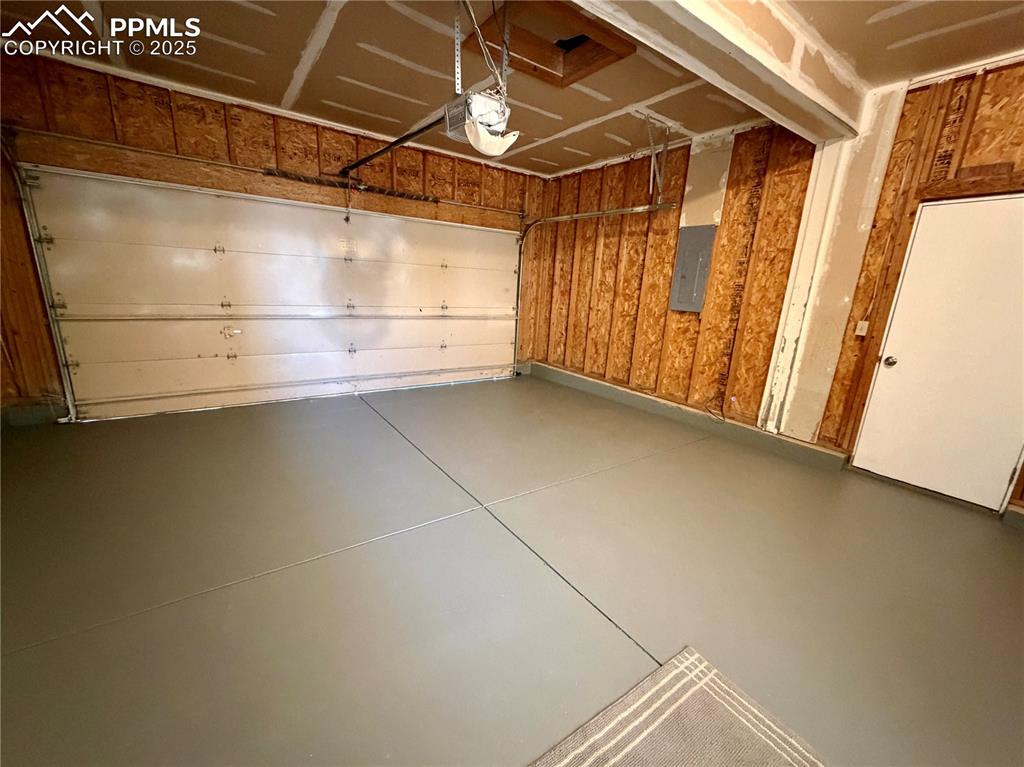 Image 34 of 38: Garage featuring electric panel and a garage door opener