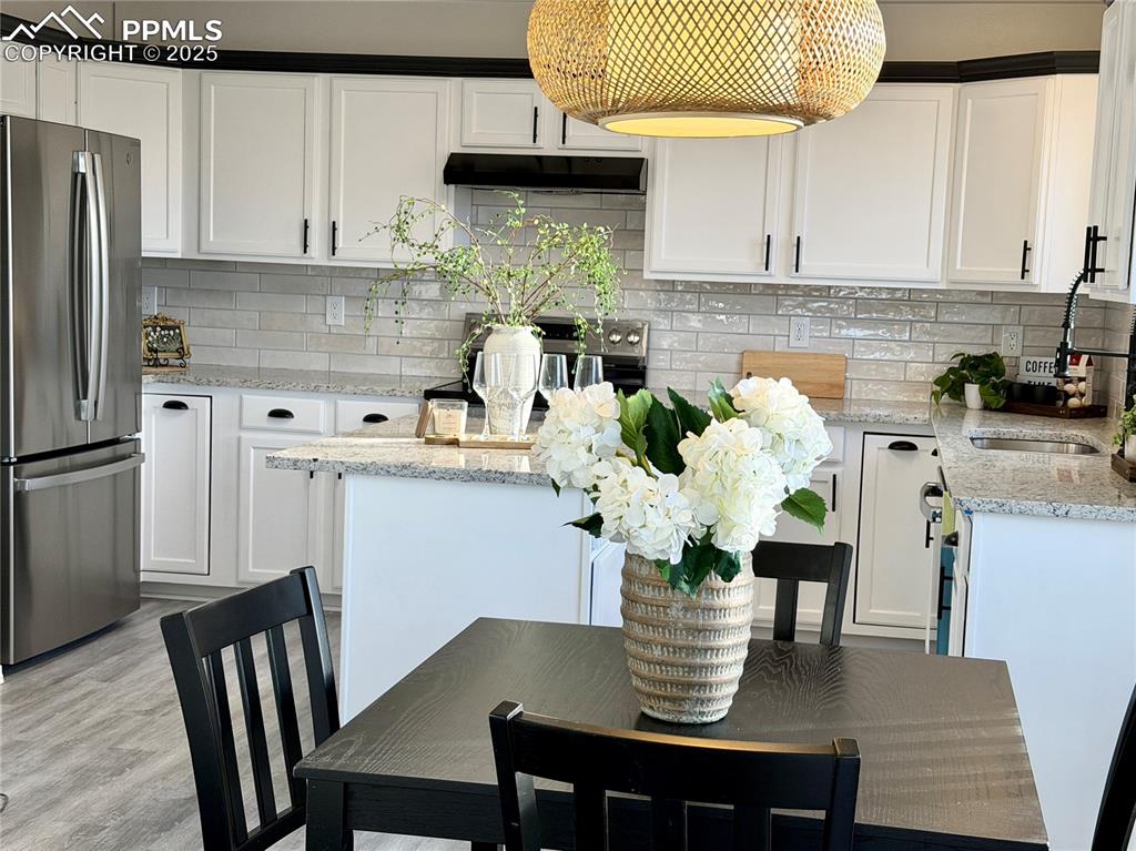 Image 7 of 38: Kitchen featuring freestanding refrigerator, tasteful backsplash, light sto