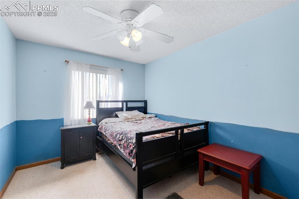 Image 21 of 34: Bedroom featuring a textured ceiling, light colored carpet, a ceiling fan,