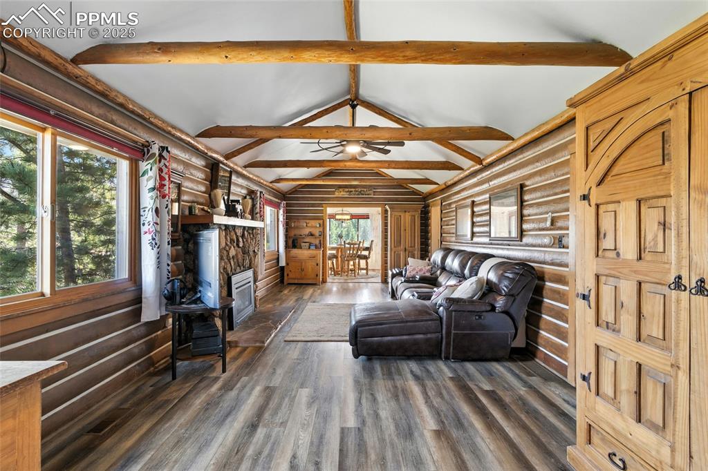 Image 16 of 43: Living room featuring rustic walls, dark wood-type flooring, a stone firepl