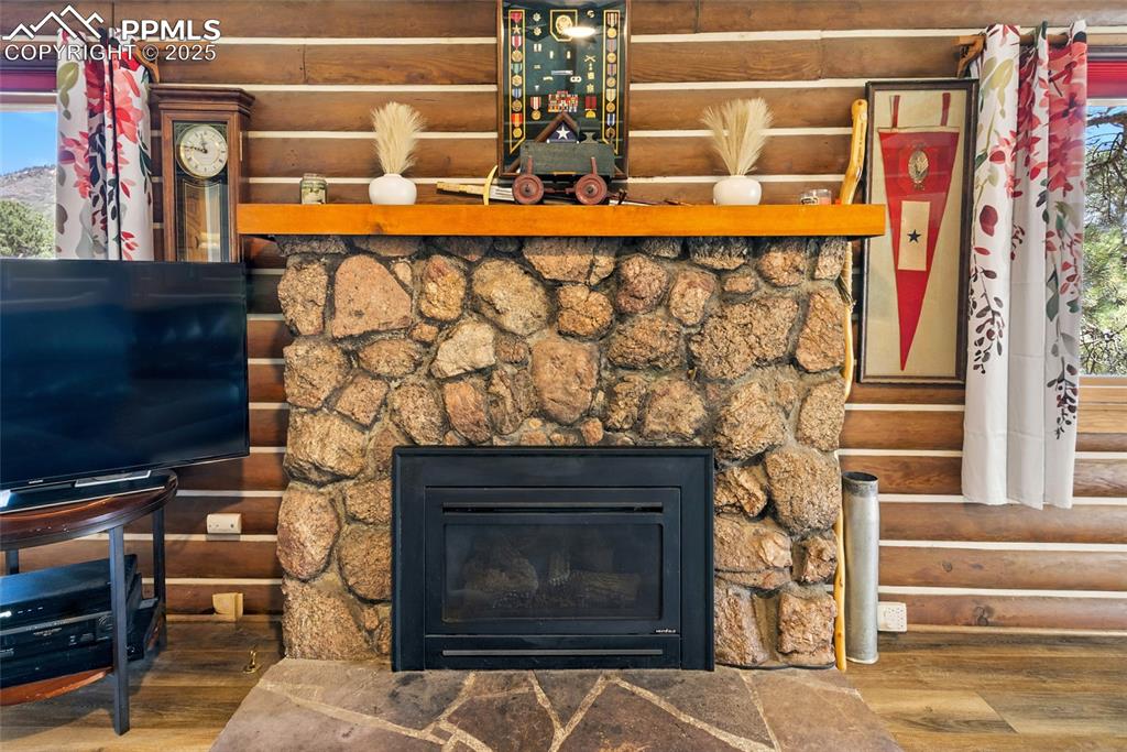 Image 18 of 43: Detailed view of wood finished floors, a stone fireplace, and rustic walls