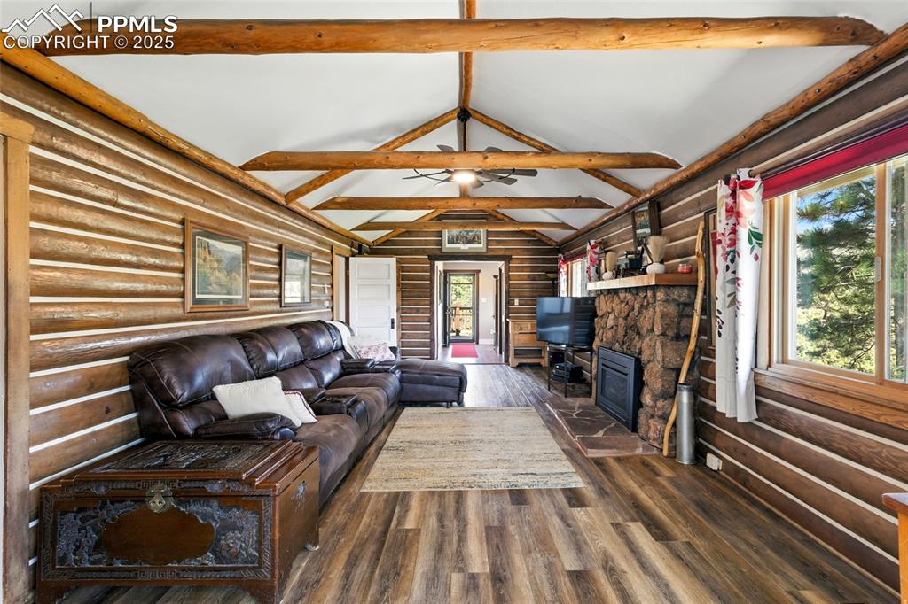 Image 21 of 43: Living room featuring rustic walls, dark wood-style flooring, and a firepla