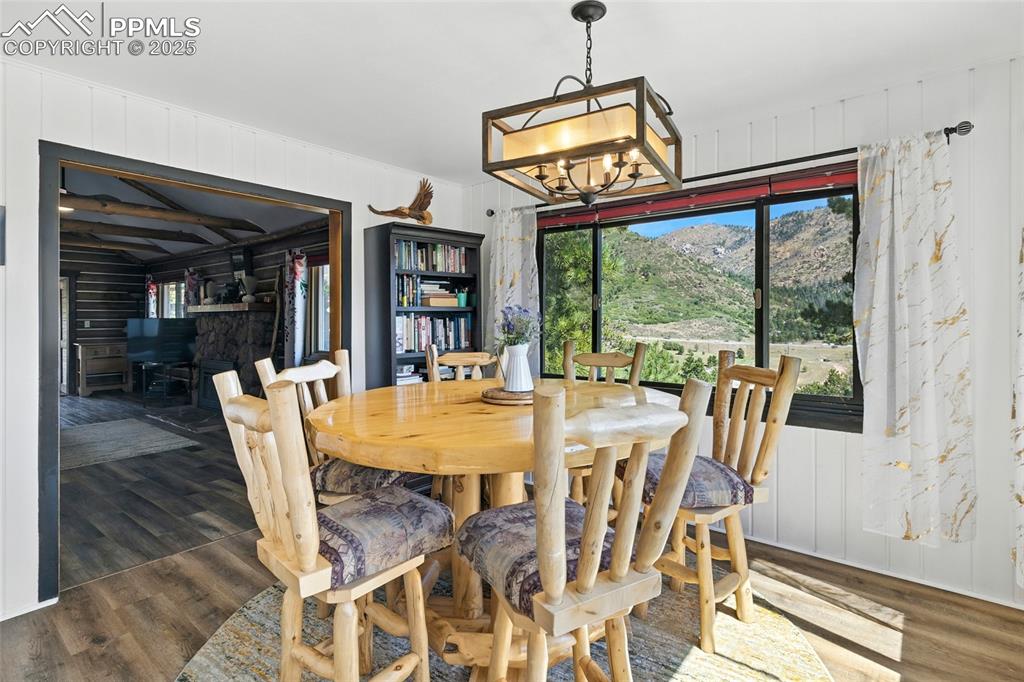 Image 23 of 43: Dining space with wood walls, dark wood-type flooring, and a chandelier