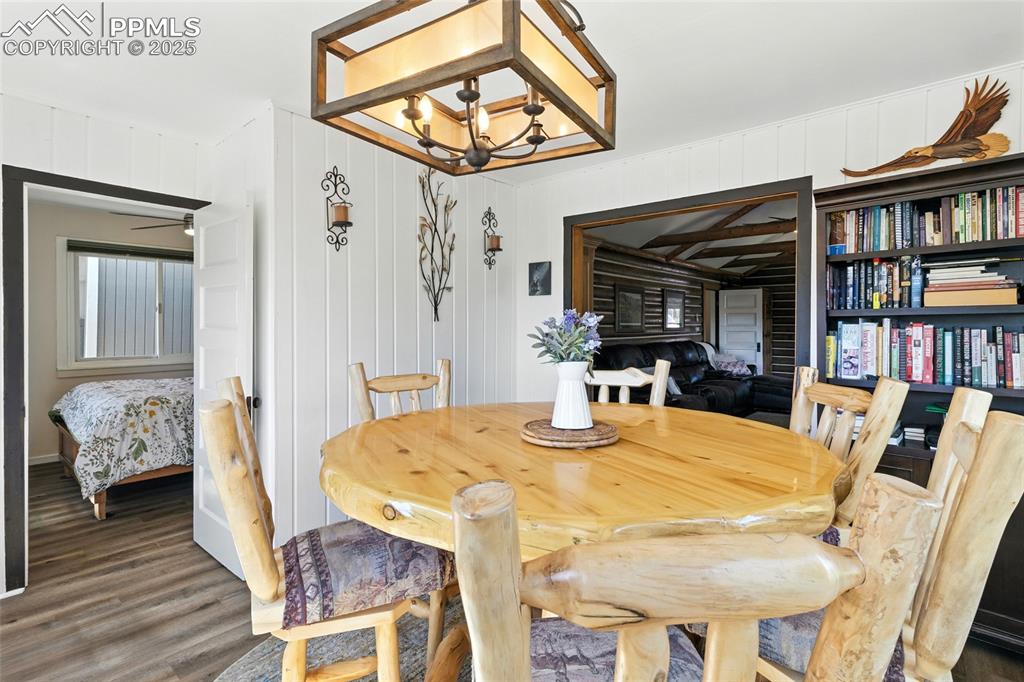 Image 24 of 43: Dining space with a chandelier, wood finished floors, and wood walls