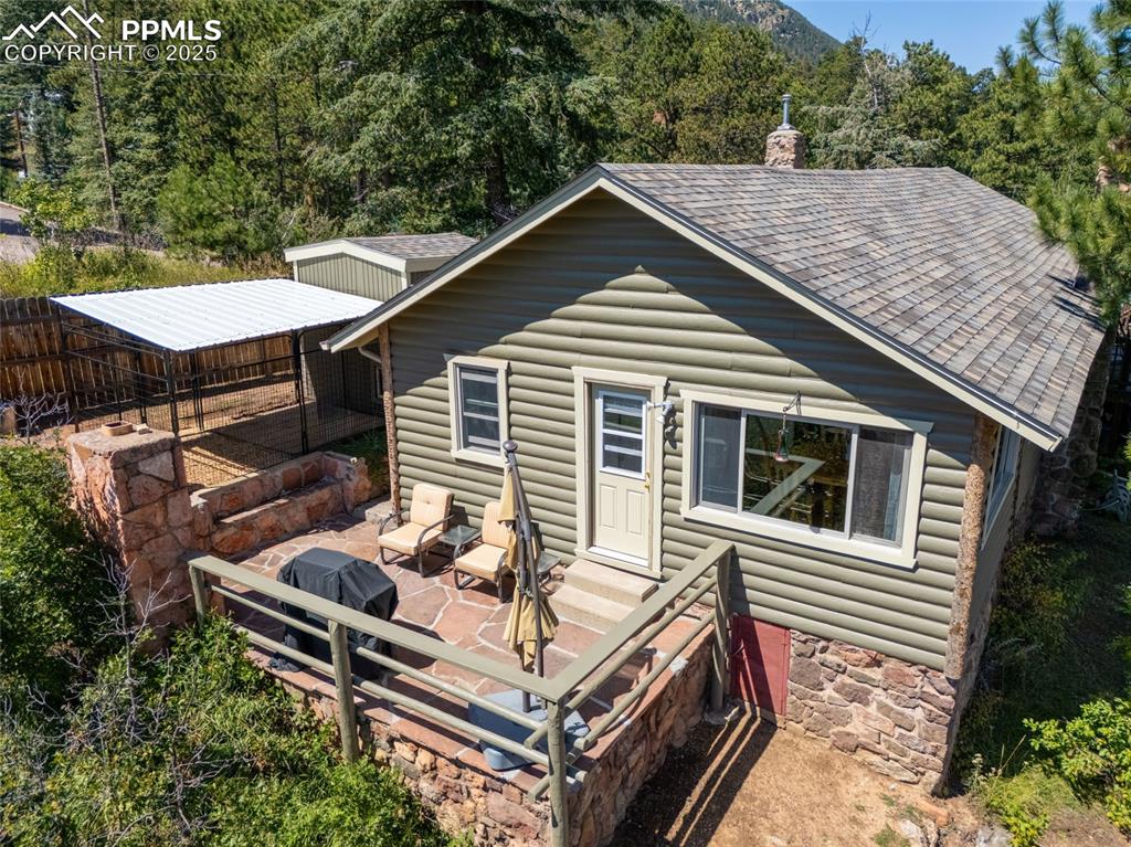 Image 9 of 43: Rear view of house with a patio, log veneer siding, a chimney, and a shingl