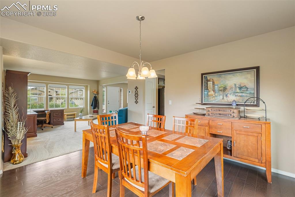 Image 10 of 50: Dining room featuring a desk, dark wood-style floors, and a chandelier