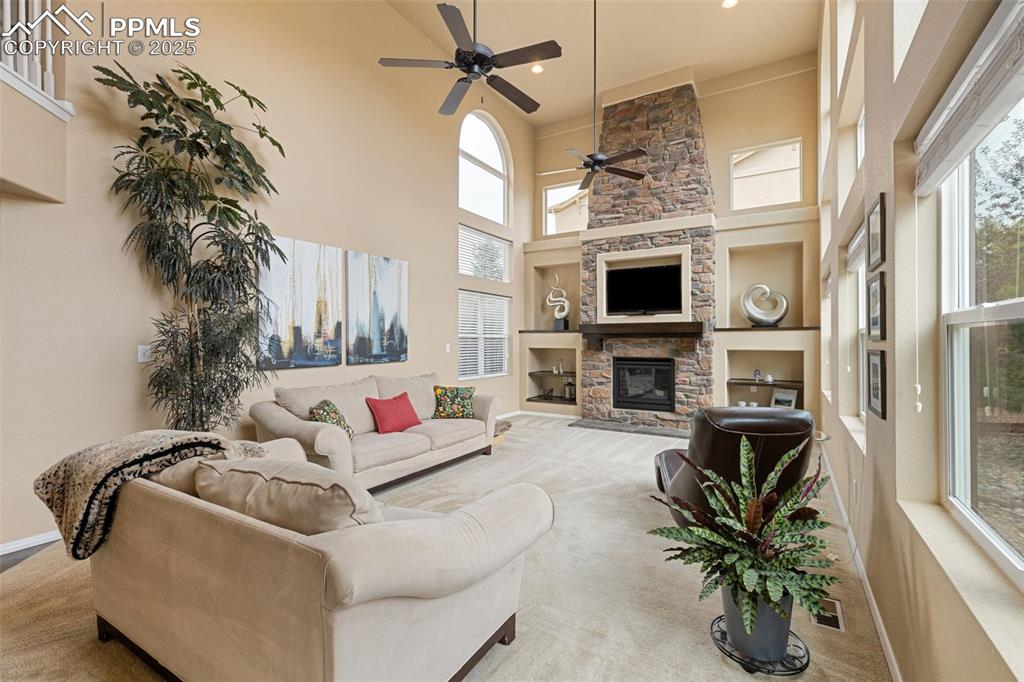 Image 14 of 50: Living room featuring a ceiling fan, a fireplace, carpet flooring, built in