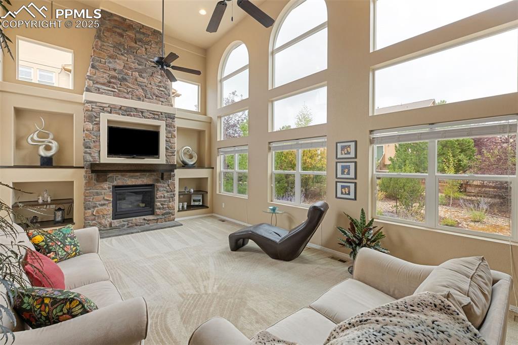 Image 15 of 50: Carpeted living room with a towering ceiling, a stone fireplace, a ceiling 
