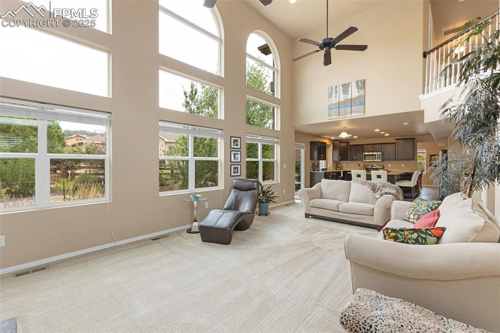 Image 16 of 50: Living area with light carpet, a ceiling fan, and recessed lighting