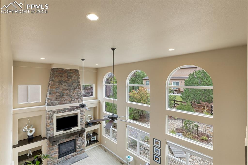 Image 17 of 50: Living area featuring a fireplace, a towering ceiling, recessed lighting, a