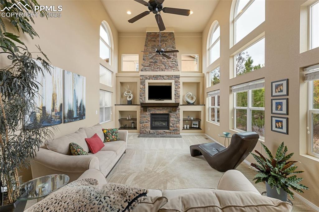 Image 2 of 50: Living room with a ceiling fan, built in shelves, a fireplace, a high ceili