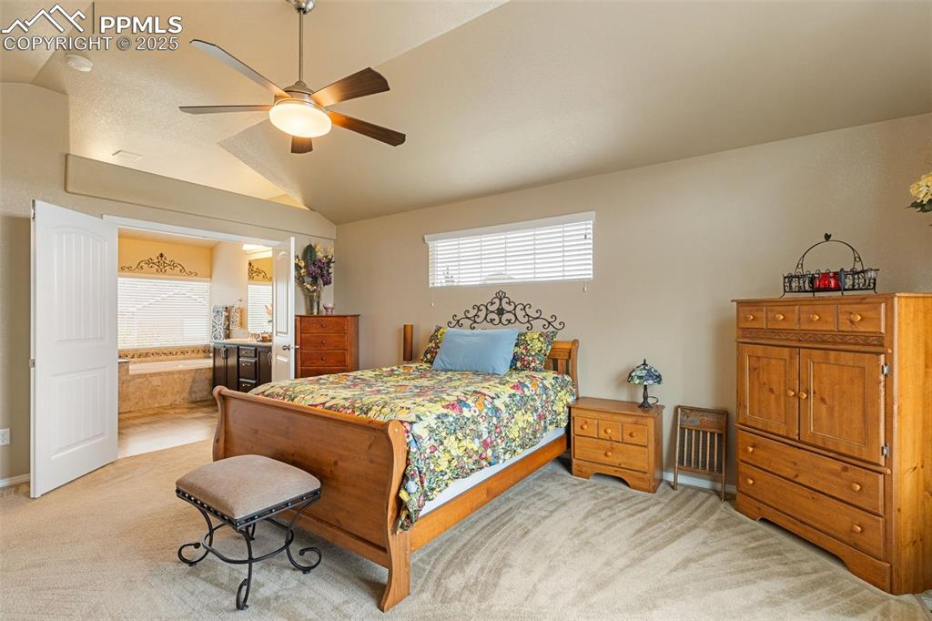 Image 20 of 50: Bedroom featuring light carpet, lofted ceiling, ceiling fan, and connected 