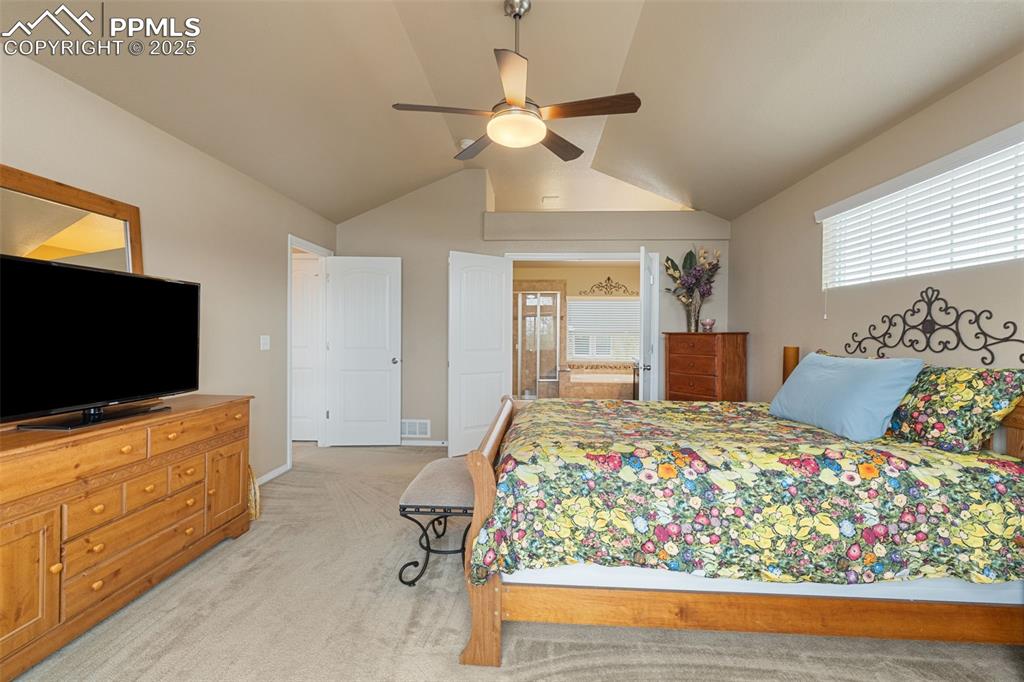 Image 22 of 50: Bedroom featuring light colored carpet, a ceiling fan, lofted ceiling, and 