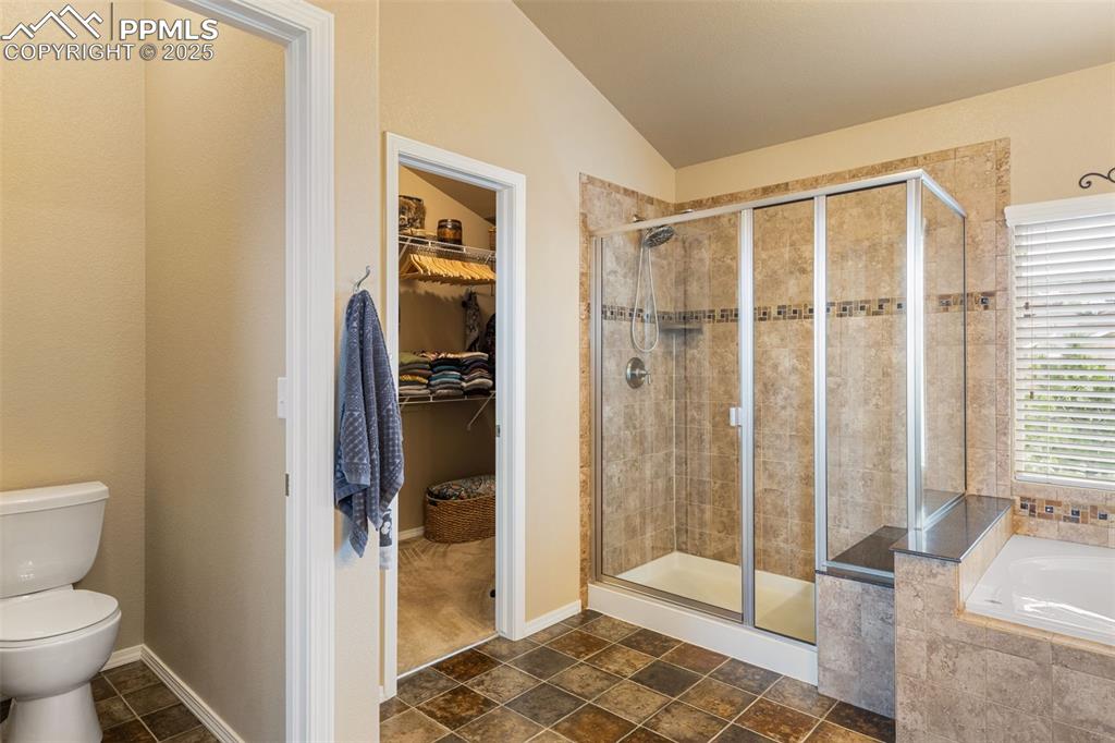 Image 25 of 50: Full bathroom with a shower stall, a garden tub, lofted ceiling, and a spac