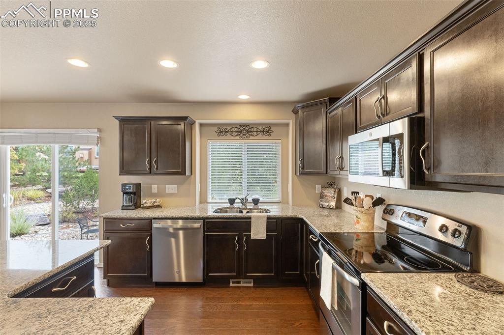 Image 3 of 50: Kitchen with appliances with stainless steel finishes, dark brown cabinetry